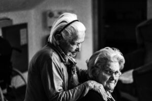 Black and white photo of two senior ladies hugging and smiling