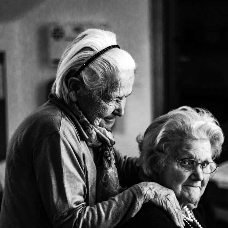 Black and white photo of two senior ladies hugging and smiling