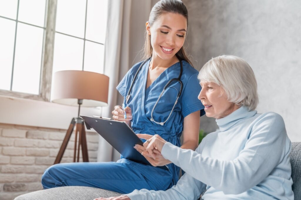 Smiling senior woman reading medical test results in the hands of a nurse visiting her in assisted living facilities