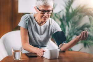 Senior lady testing her blood pressure at home using health wearables