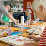 Elderly woman painting a watercolour flower in one of the Coquitlam senior recreation programs