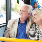 Elderly couple smiling as they look out the bus window