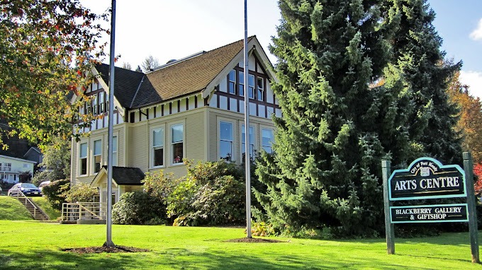 Grassy frontage with a sign for the Port Moody Arts Centre and the historic building in the background