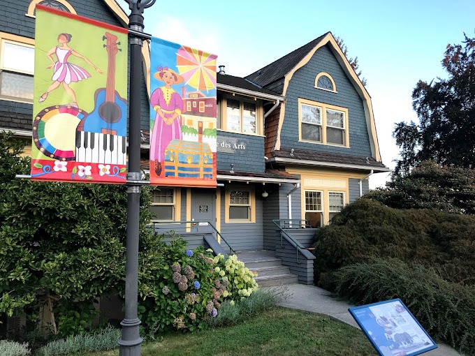 Colourful banners and a historical plaque outside the historic blue building where Place des Arts is housed