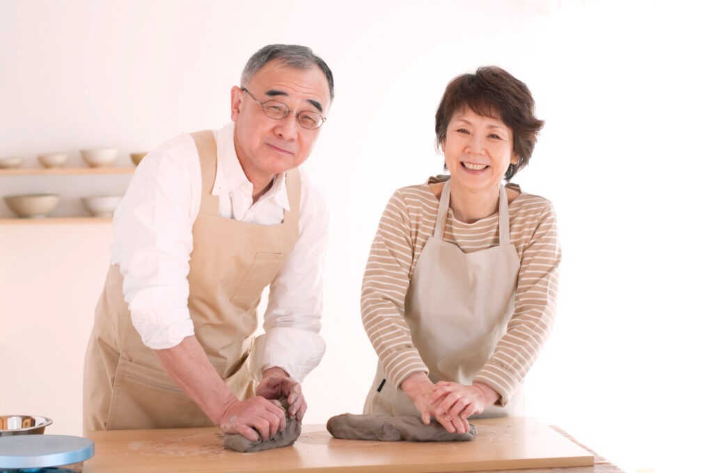Old couple kneading raw clay and smiling