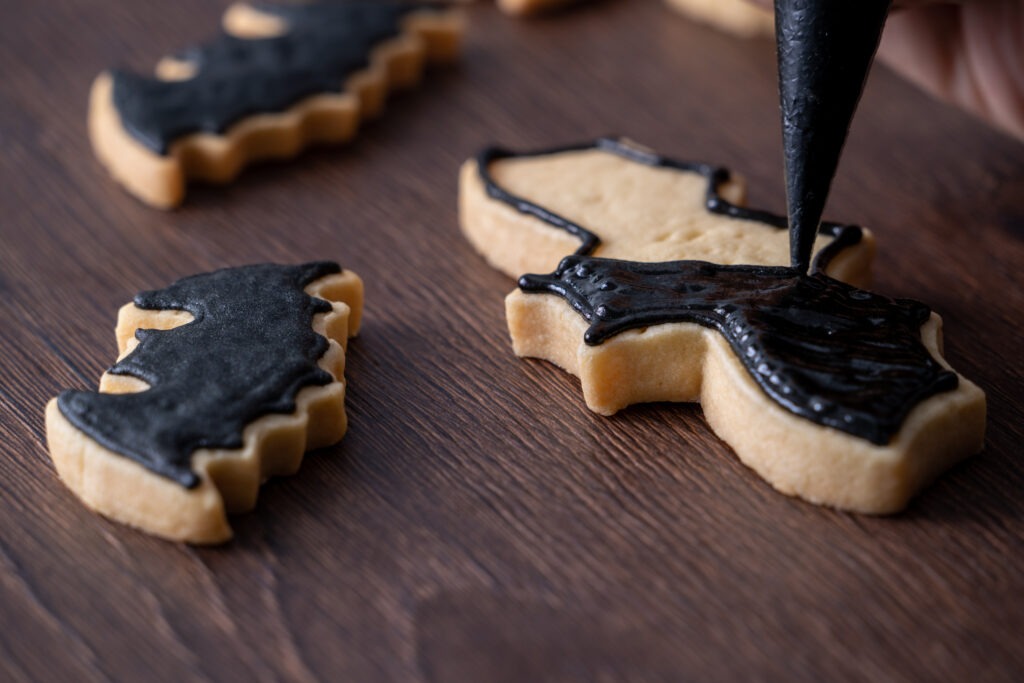 Close up of decorating cute Halloween bat sugar cookies with frosting