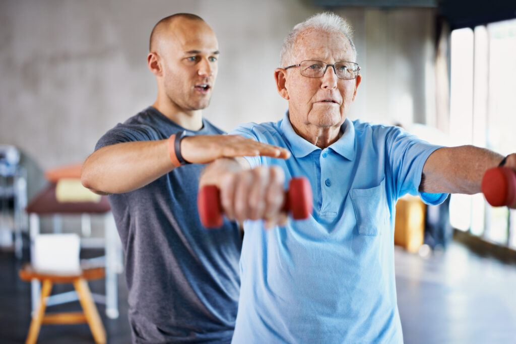 Physiotherapist helping a senior man with weights