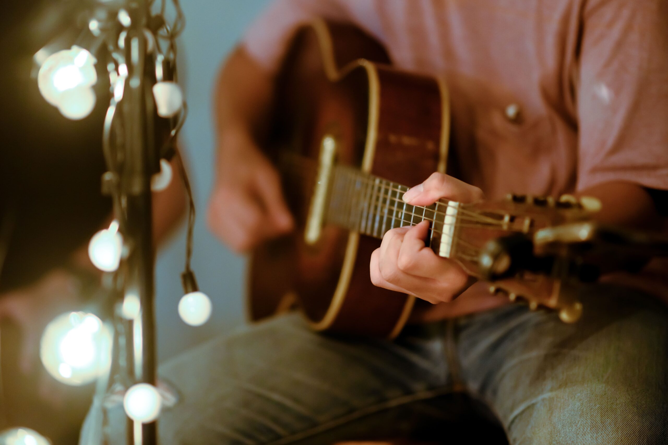 Man sitting playing acoustic guitar with a microphone stand in the front