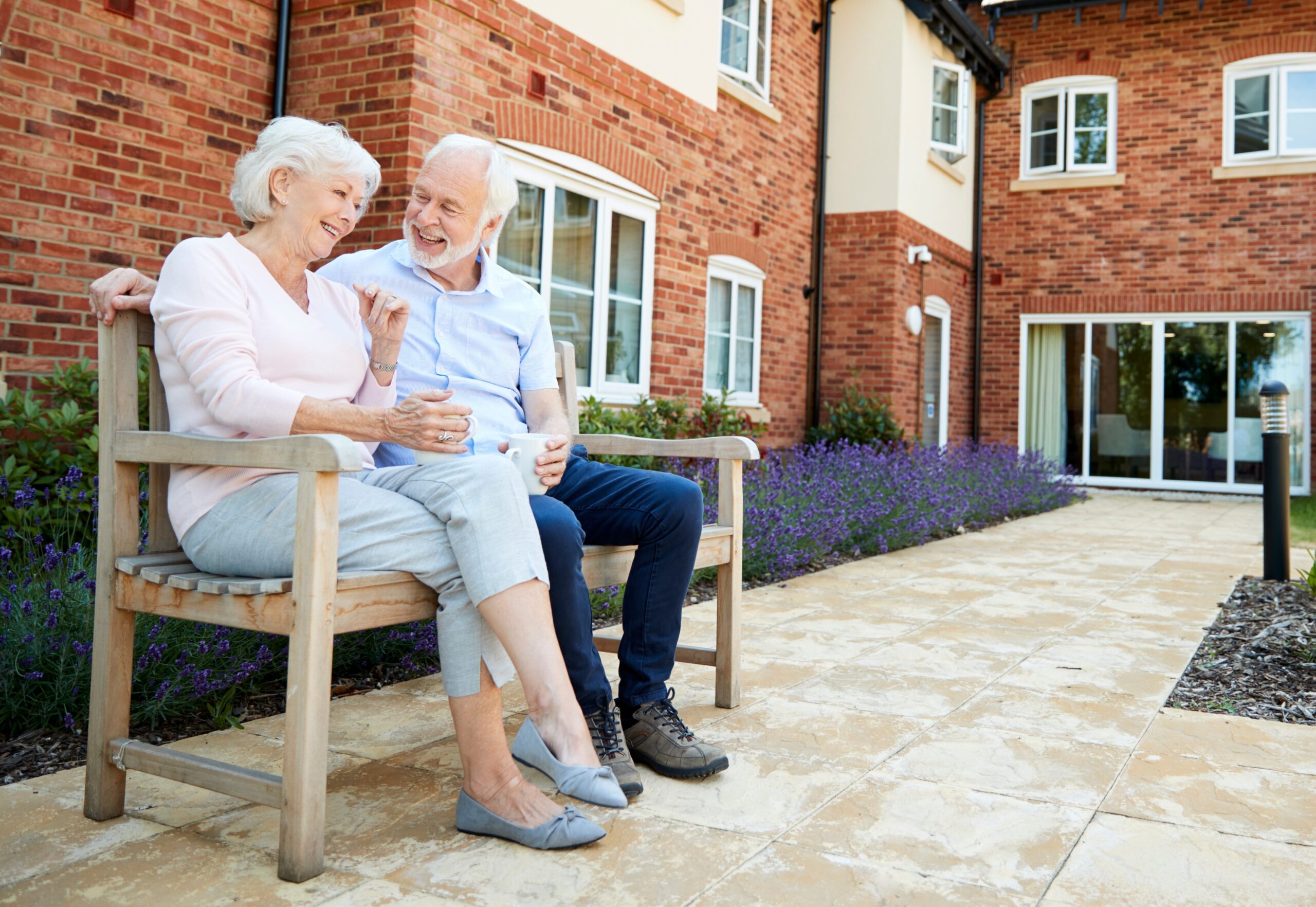Retired couple sitting on a bench in the courtyard of an independent living residence