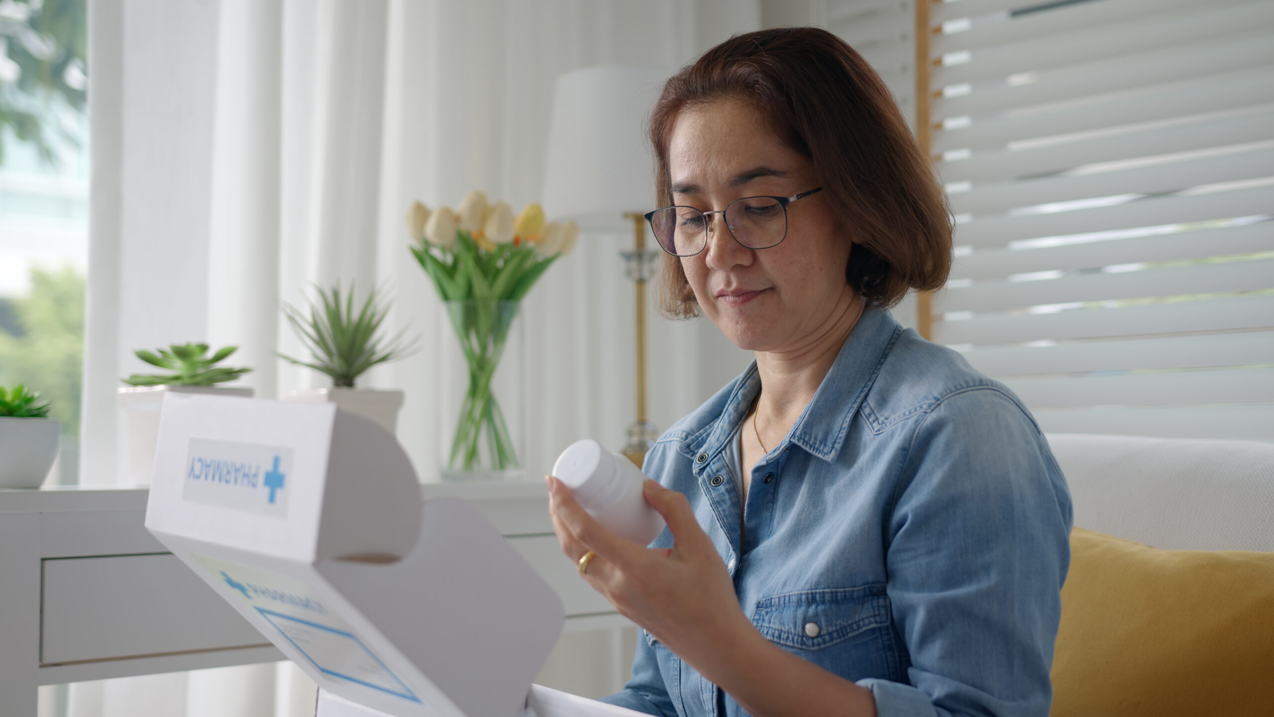 Asian lady examining the pill bottle in her medication delivery