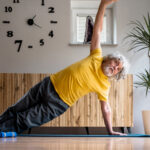 Senior man doing a side plank in his living room