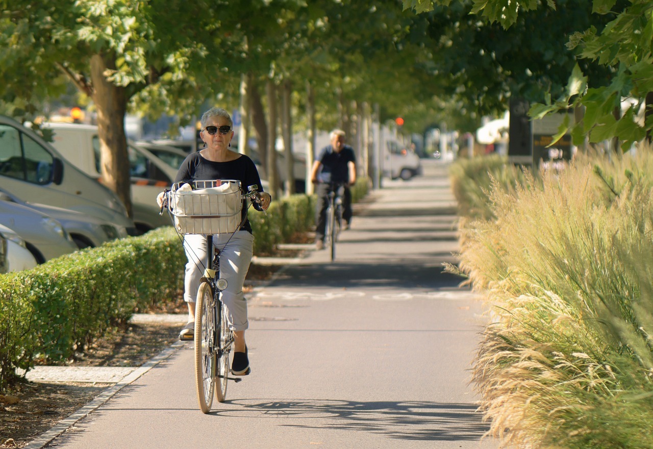 Senior lady cycling down the side walk