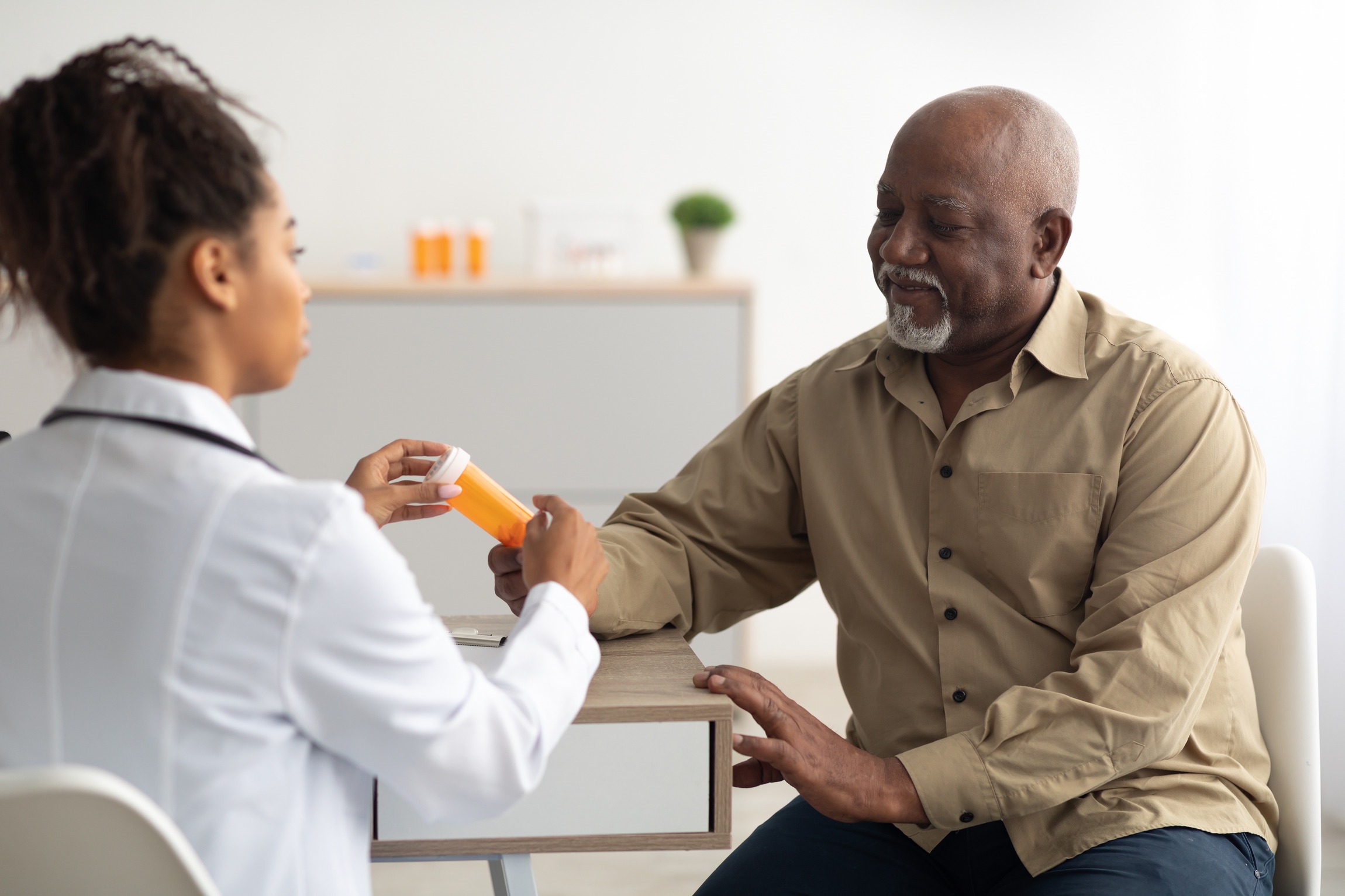 Elderly man consulting with a female doctor about medication