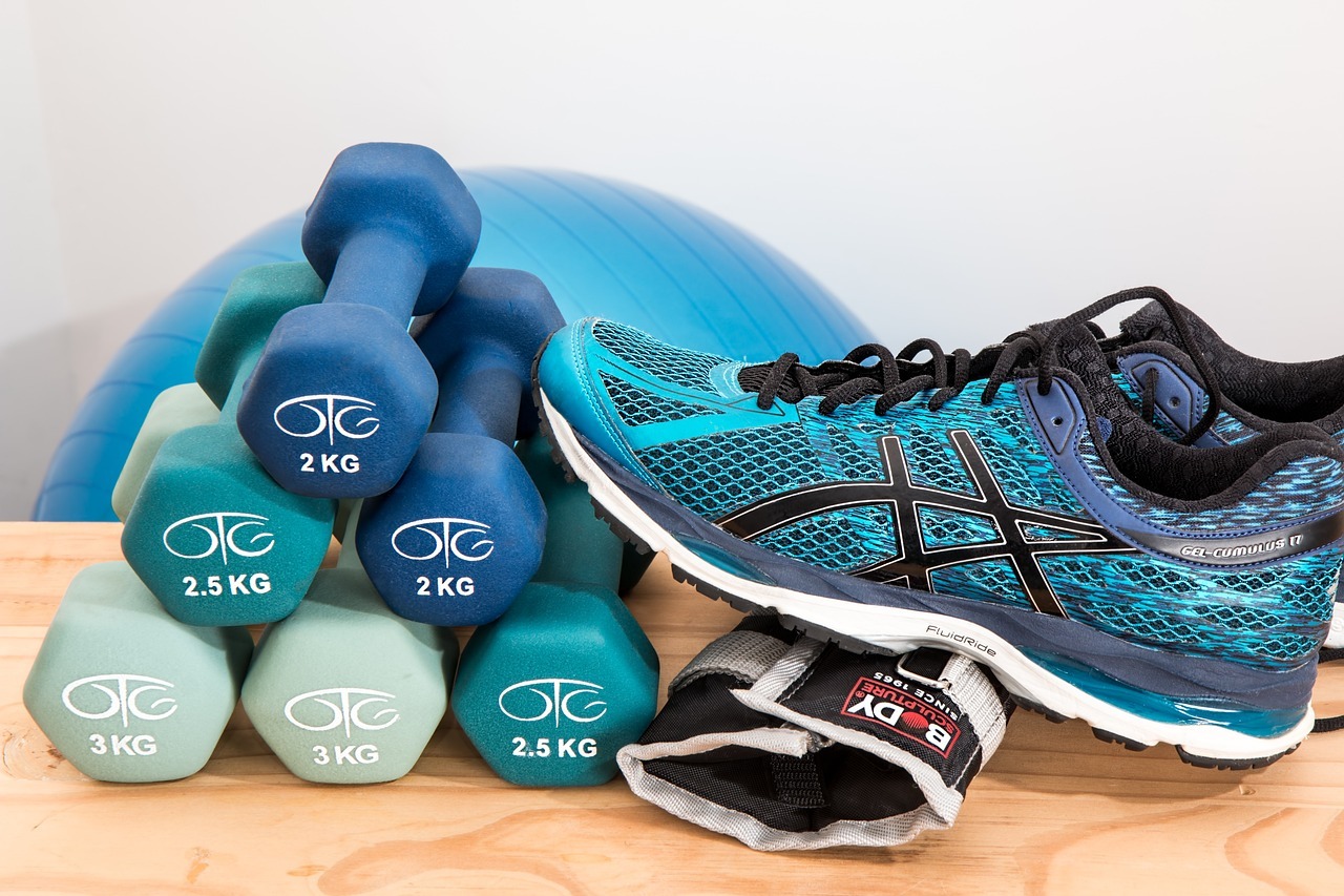 Running shoes sitting next to ankle weights, small dumbells, and a Swiss ball.