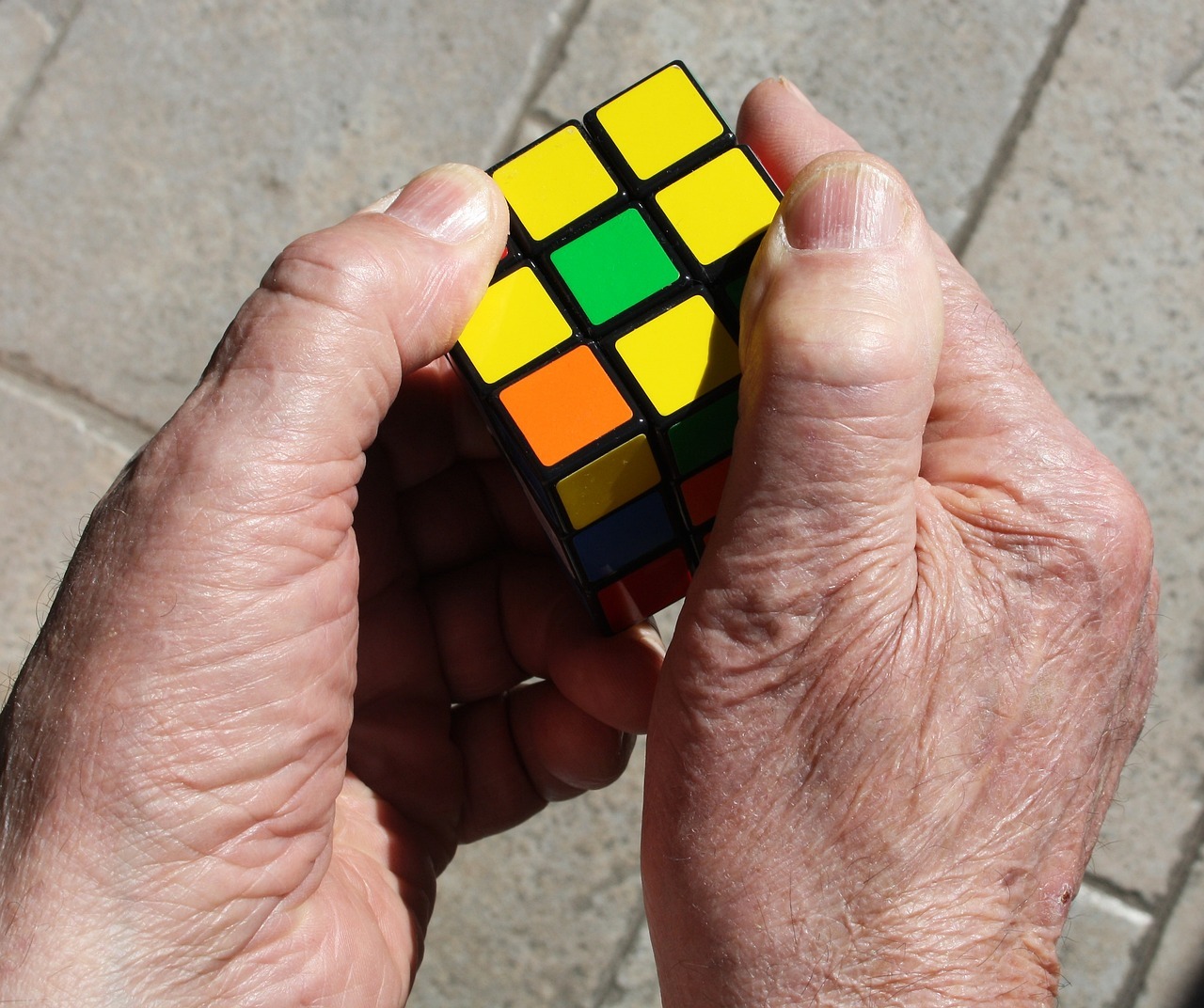 Elderly man working on solving a Rubik’s cube