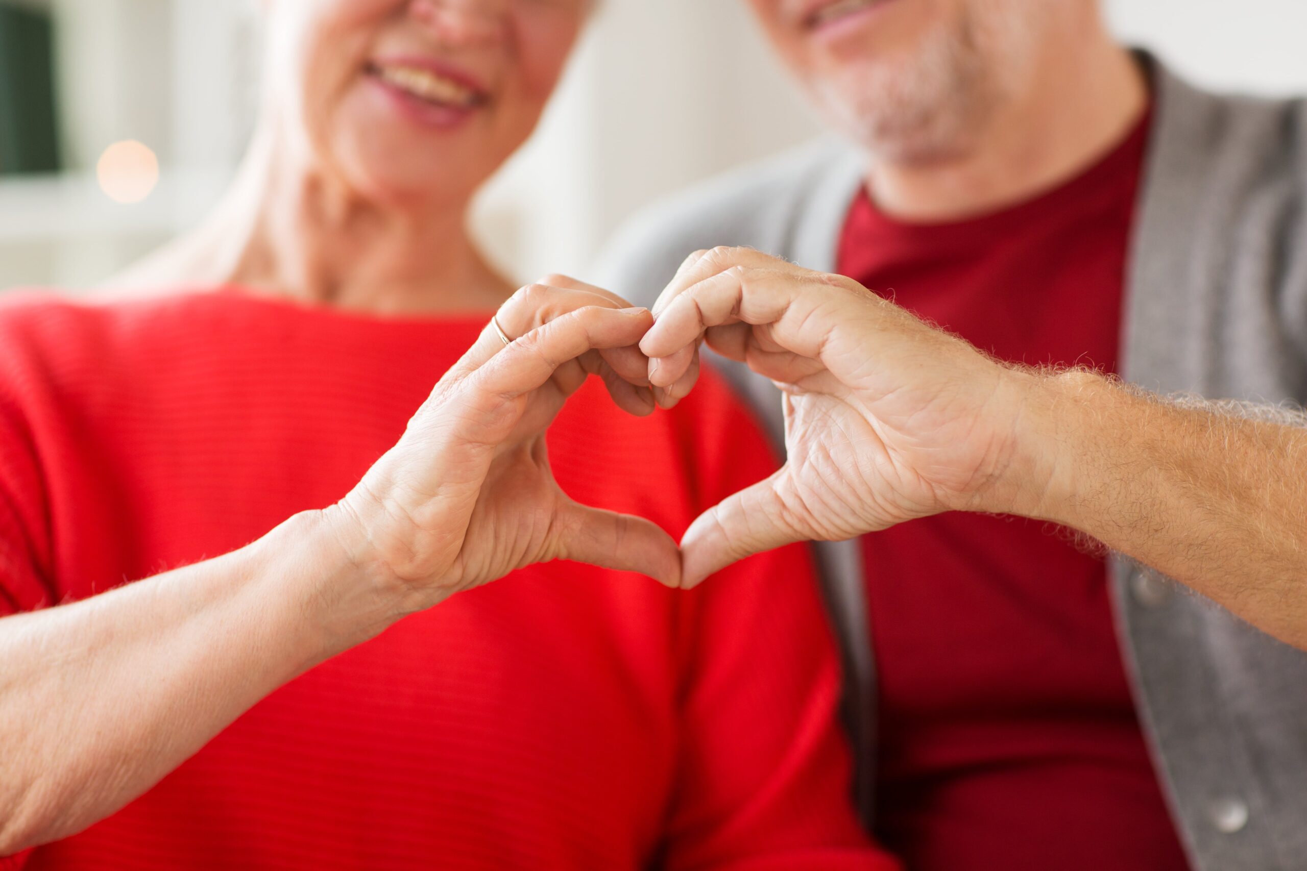Close-up of senior couple showing hand heart sign