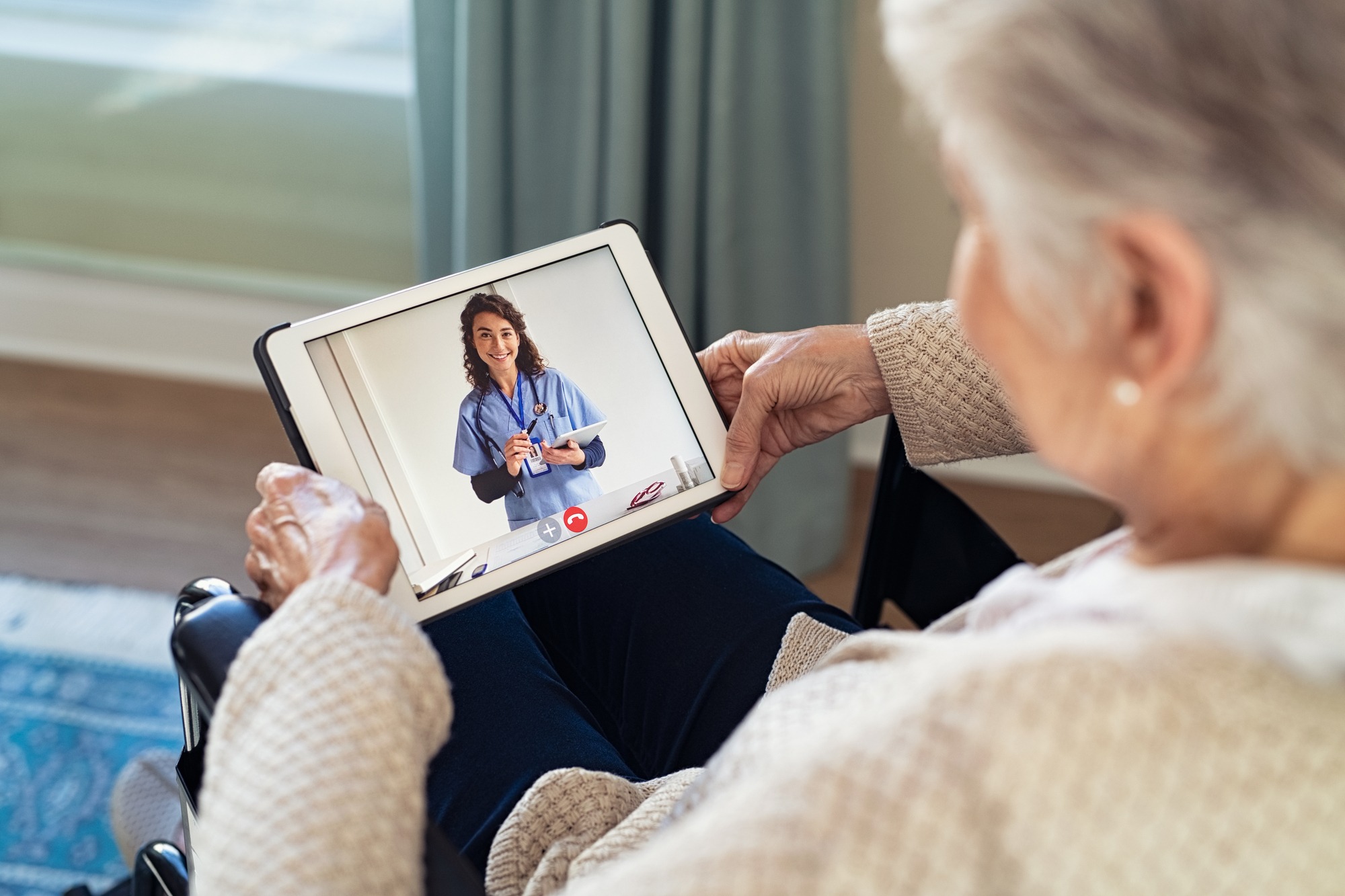 Older woman is making video call with doctor on laptop and consulting about medicine
