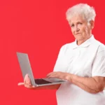 Senior Woman Using Laptop on Red background