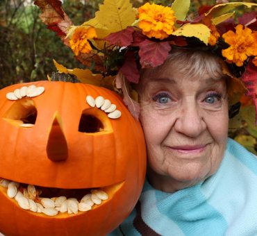 Happy old lady posing with a carved pumpkin