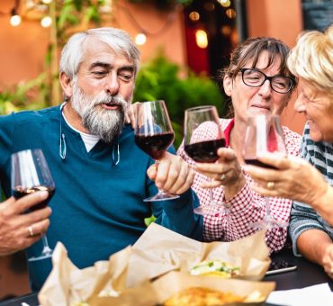 Happy group of seniors having fun toasting red wine at a restaurant