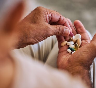 Senior man holding a handful of nutritional supplements