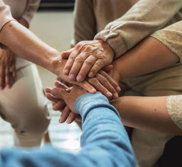 Group of elderly people joining hands together