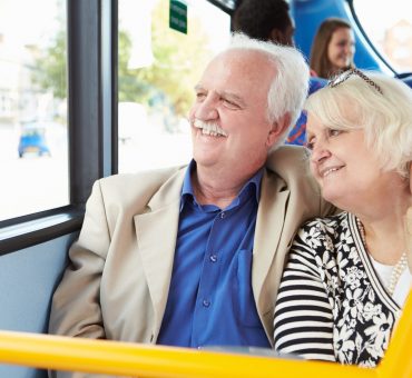 Elderly couple smiling as they look out the bus window