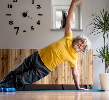 Senior man doing a side plank in his living room