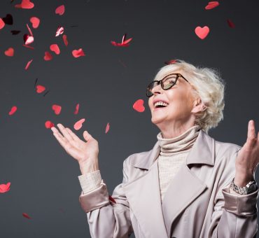 Senior lady joyously looking up into heart-shaped confetti