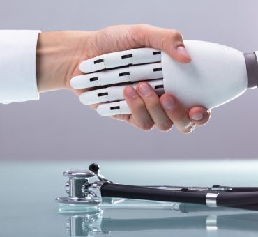 Doctor and robot shaking hands over stethoscope