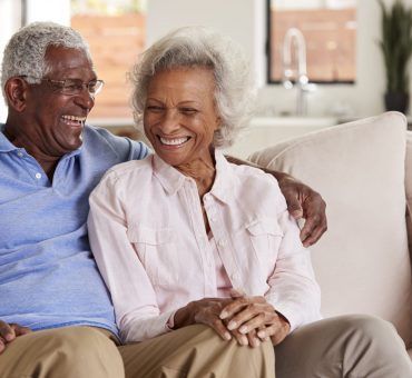 Loving senior couple sitting on sofa at home and laughing together