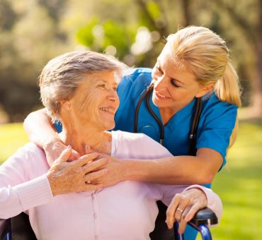 Caring nurse with senior patient in a wheelchair outdoors in a park