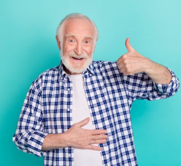 Cheerful senior touching his belly while giving a thumbs-up