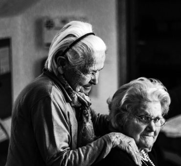 Black and white photo of two senior ladies hugging and smiling