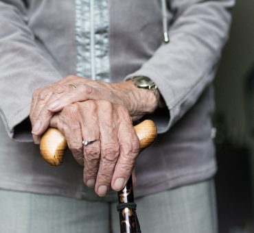 Elderly lady standing with a walking cane in her living room