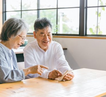 Senior couple sitting at a wooden table in a light-filled room using one of their healthcare apps in Canada.