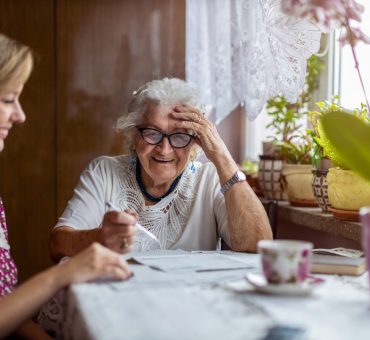 Elderly lady sitting at a table with her daughter choosing between retirement homes in Coquitlam