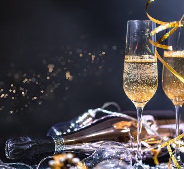 Two glasses and a bottle of champagne surrounded by New Year’s Eve decorations